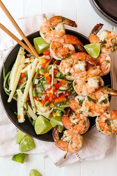 a bowl filled with shrimp and veggies next to chopsticks on a table