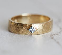 a gold wedding band with a blue diamond