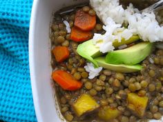 a white bowl filled with lentils, carrots and avocado next to rice