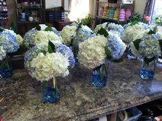 blue and white flowers are in vases on the counter