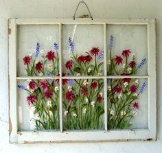 an old window with flowers painted on the glass and hanging from it's side