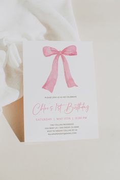 a card with a pink bow on it is laying on top of a white sheet