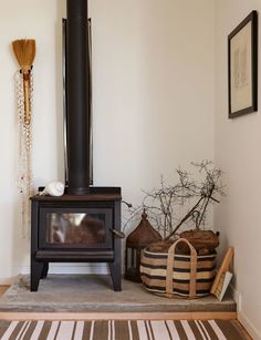 a wood burning stove sitting in the corner of a room next to baskets and brooms