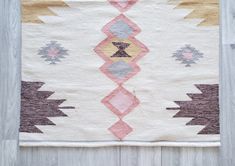 an old rug is displayed on a wooden floor with wood planks in the background