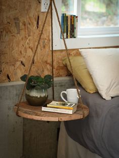 a bed with a wooden shelf holding books and a coffee cup on top of it