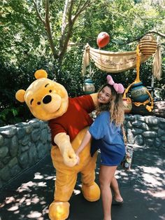 a woman poses with a large winnie the pooh mascot