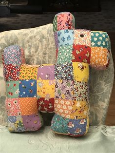 two colorful pillows sitting on top of a white chair next to a pillow that is made out of patchwork fabric