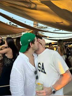 two men kissing each other at an outdoor event