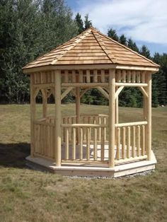 a wooden gazebo sitting on top of a lush green field