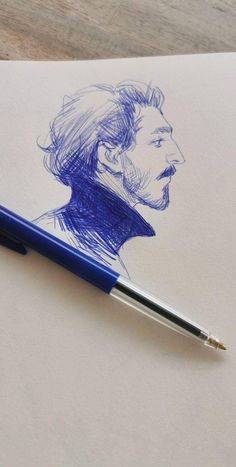 a blue pen sitting on top of a piece of paper next to a drawing of a man