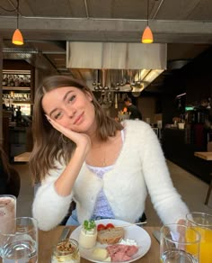 a woman sitting at a table with food and drinks