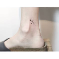 a small tattoo on the ankle of a woman's foot, with an arrow