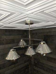 three lamps hanging from the ceiling in a room with wood paneled walls and ceilings