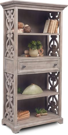 the bookcase has three shelves with books on top and two vases in front