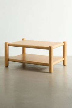 a small wooden table sitting on top of a cement floor next to a white wall