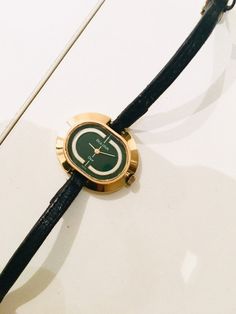 14k gold plated 70s Dior by Bulova wrist Watch  This is genuine and purchased in the early 70s. This is a wind up watch and still works. The gold is in great condition, the actual watch face has some light scratches but no cracks, strap in fair condition.  gold and dark green face  3x2x0.5 cm Gold And Dark Green, Cartier Gold, Vintage Designer Bags, Fendi Sunglasses, Striped Bags, Leather Hobo Bag, Leather Hobo, Wrist Watches, Womens Watches