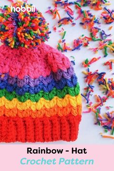 a knitted rainbow hat with pom - pom on top and sprinkles around it