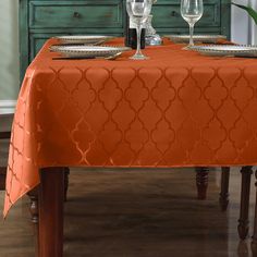 the table is set with two wine glasses and an orange tablecloth on top of it