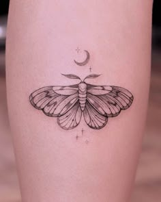 a small moth tattoo on the right thigh, with a crescent moon in the background