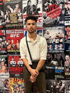 a man standing in front of a wall full of wrestling posters and magazines with his hands on his hips