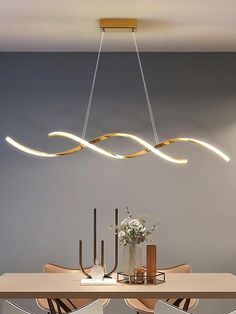 a modern chandelier hangs over a dining room table with chairs and vases