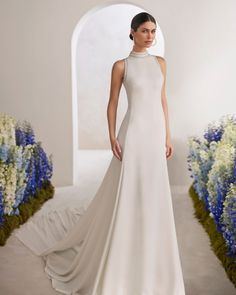 a woman in a white dress standing next to flowers