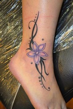 a woman's foot with a purple flower tattoo on the side of her leg