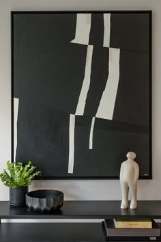 a black and white painting sitting on top of a table next to a potted plant