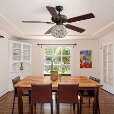 a dining room table with four chairs and a ceiling fan in the middle of it