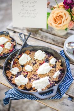 two blueberry cobbles are sitting on a picnic table with flowers and a sign