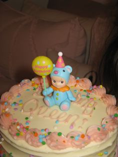 a birthday cake with a teddy bear holding a balloon