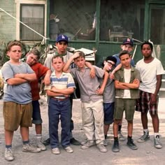 a group of young boys standing next to each other in front of a building with green shutters