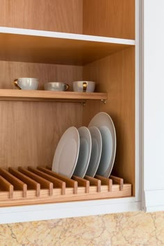 plates and bowls are stacked in a wooden cabinet