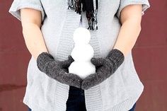 a woman holding a snowman in her hands with a scarf around it's neck