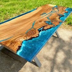 a table made out of wood with blue paint on the top and bottom, sitting in front of some grass