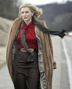 a woman walking down the street wearing a coat and scarf