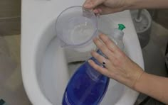 a person is using a bottle to flush a toilet