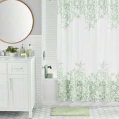 a white bathroom with green shower curtains and a round mirror on the wall above the sink