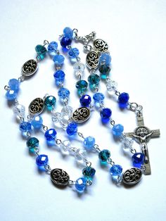 This mixed blue Lutheran rosary is made with AB faceted, transparent, 8x6 mm glass rondelles. The colors include light blue, dark cyan, cornflower blue. clear, and dark blue. The Sunday beads are 12mm, zinc based, pewter ovals, while the crucifix is Italian made, oxidized silver. I hand turned and linked the silver-plated wires. It is made in the Longworth Lenten pattern of six sets of seven beads. It measures about 23 inches around and has a 5-inch cross drop. This rosary will be slipped into a velvet bag and shipped in a bubble mailer. Dark Cyan, Bubble Mailer, Velvet Bag, Oxidized Silver, Cornflower Blue, Prayer Beads, Rosary, Bead Charms, Silver Plate