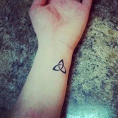 a person's hand with a small tattoo on the wrist and an arrow in the middle