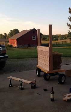 there is a small wooden cart with some wine bottles on it and other items around it