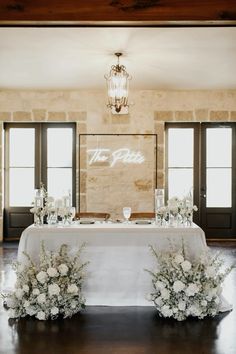 the table is set up with white flowers and greenery for an elegant wedding reception