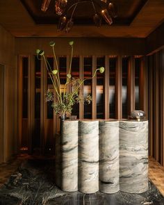 three vases with flowers in them sitting on a marble counter top next to wooden paneled walls