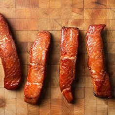 four raw salmons are lined up on a cutting board, ready to be cooked