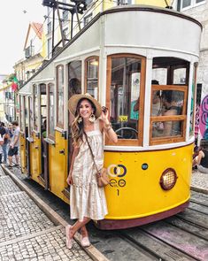 a woman standing next to a yellow trolley car