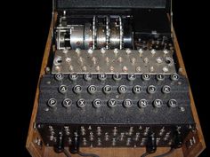 an old fashioned typewriter sitting on top of a wooden table next to a black background