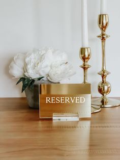 a table with two candles and a sign on it that says reserved next to some flowers