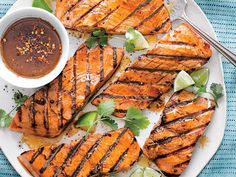 grilled salmon with barbecue sauce on a white platter next to limes and cilantro