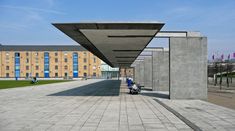 a person sitting on a bench in the middle of a walkway with buildings in the background