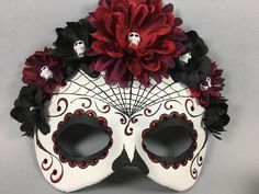 a white mask with red and black flowers on it